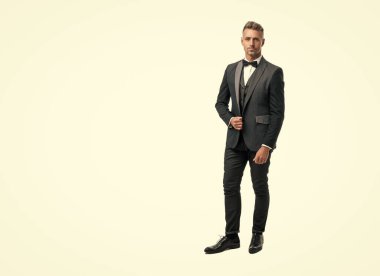 Beyaz arka planda boyun yayı olan smokin giymiş iş adamı. tam uzunluk.