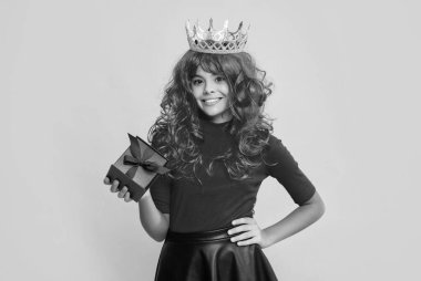 Sarı arka planda mevcut kutusuyla taç giymiş gülümseyen kız..