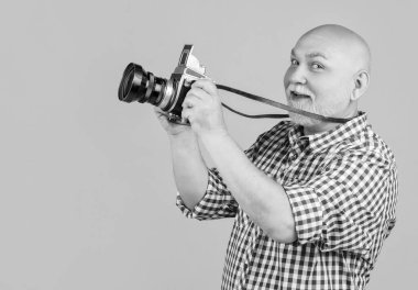 Sarı baqckground 'da retro fotoğraf makinesi olan mutlu yaşlı bir adam..