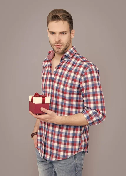 sale of present for man wear checkered shirt in studio. birthday present for man. sale and discount. present sale concept. man hold present at sale isolated on grey background.