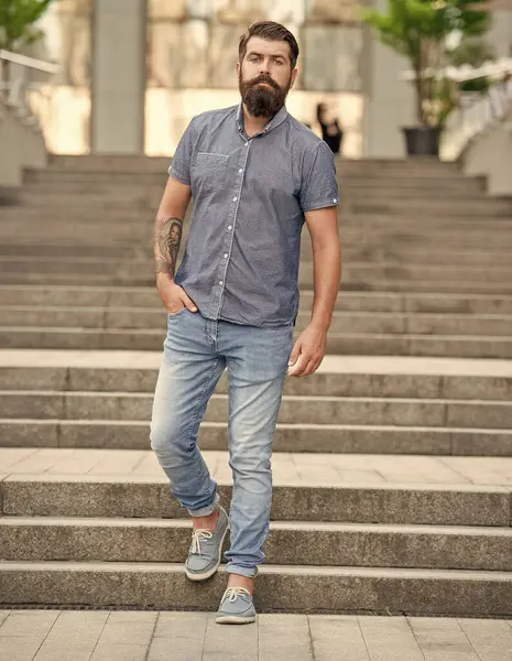 bearded hipster walking downstairs. full length of hipster with beard. caucasian hipster outdoor.