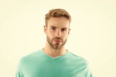 Genç, tıraşsız bir adam yüzü beyaz arka planda izole edilmiş. Tişörtlü traşsız bir adamın yüzü. Tıraşsız erkek derisinin portresi. Traşsız bir adamın stüdyo fotoğrafı..