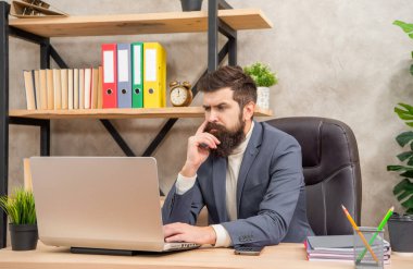 Serious professional man in suit working on work computer in office, employee.