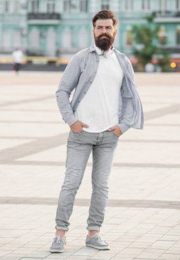 bearded man standing with headphones. full length of man with beard. brutal casual man outdoor.