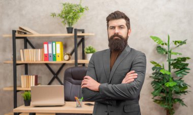 mature entrepreneur in jacket standing crossed hands at office with copy space, charisma.