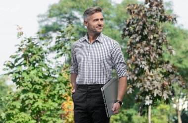 smiling man hold laptop. man freelancer outdoor. business man with pc.