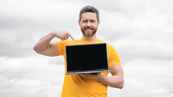 man presenting computer on sky background. copy space.