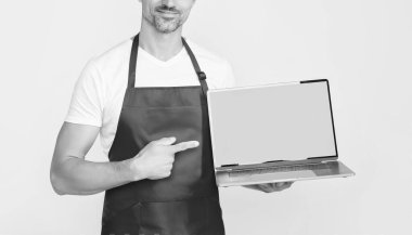 Önlüklü neşeli olgun adam dizüstü bilgisayarına kopyalama alanı sunuyor..