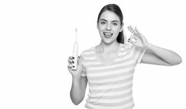 Beyaz arka planda elektrikli diş fırçası olan mutlu genç bir kadın. Tamam.