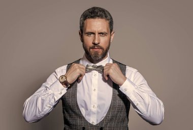 Stüdyodaki smokinli adamın yüzü. Smokin giyen bir adamın fotoğrafı. Smokin giyen adam resmi takım elbise giyer. Smokinli adam gri arka planda izole edilmiş..