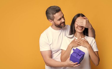 Sürpriz hediyeli çift, kopyalama alanı. Sürpriz hediye kutusu olan tatil çifti. Tatil hediyesi olan bir çiftin fotoğrafı. Kadınlar Günü 'nde. Sarı arka planda şu anda izole edilmiş sürpriz çift.