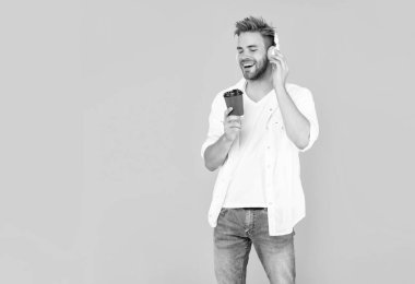 Tüylü pozitif adam müzik dinle sarı arka planda kahve iç, iç.