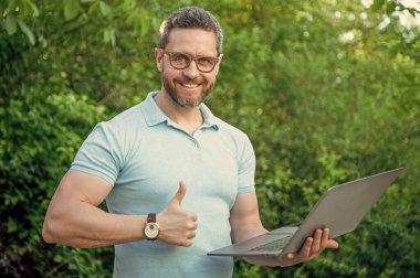 Programcı başparmağını kaldırdı. Programcı açık havada. Bilgisayarda çalışan programcı. Bilgisayarda programcının fotoğrafı..