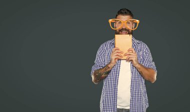 Parti gözlüklü neşeli sakallı adam kitap tutuyor..