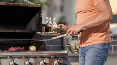Dışarıdaki adam ızgara ve barbekü tabakları pişiriyor. Dumanlı barbeküde ızgara yapan adam. Izgara maşaları hazır. Izgaracı adam barbeküde et pişiriyor..