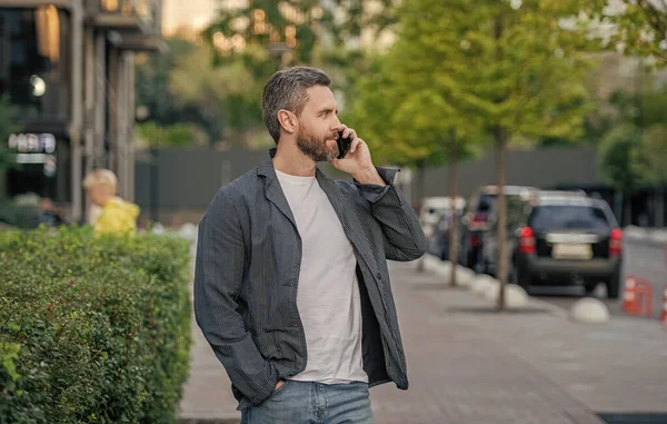 man having mobile call in the street. man call on mobile outside. photo of man call on mobile phone. man has mobile call outdoor.