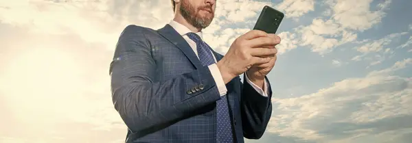 cropped view of businessman type phone message on sky background. businessman type phone message outdoor. businessman type phone message wear suit. photo of businessman type phone message.