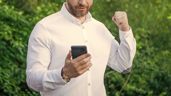 cropped view of marketing businessman hold phone. marketing businessman with phone outdoor. marketing businessman with phone work online. photo of marketing businessman with phone.