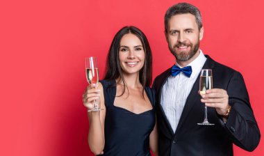 Resmi olarak bir çift. Romantik randevu kutlamaları. Sevgililer Günü. Yıldönümünü kutlayalım. Aşık çift nişanı kutluyor. Zarif çift kırmızı pankartta izole edilmiş şampanya içiyor..