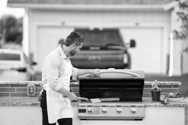 Stock image man barbecuing trout fillet outside. man barbecuing trout fillet at backyard. photo of man barbecuing trout fillet on grill. man barbecuing trout fillet.