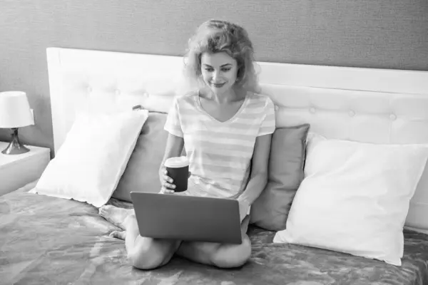 glad woman freelancer with coffee at home chat on laptop. freelancer woman work at home. home work for freelancer. woman in bed with laptop.