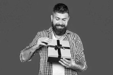 Neşeli, olgun, sakallı, gri arka planda hediye kutusu olan adam..