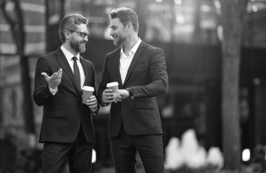 Yönetici dışarıda iş konuşuyor. Takım elbiseli bir yönetici kahve içerken iş konuşuyor. Yöneticinin kahve ile iş görüşmesi imajı. Yönetici sokakta iş konuşuyor..