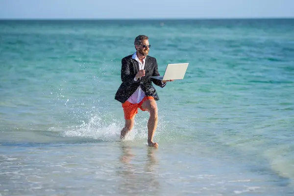 successful businessman has business success run with laptop in sea at summer vacation.