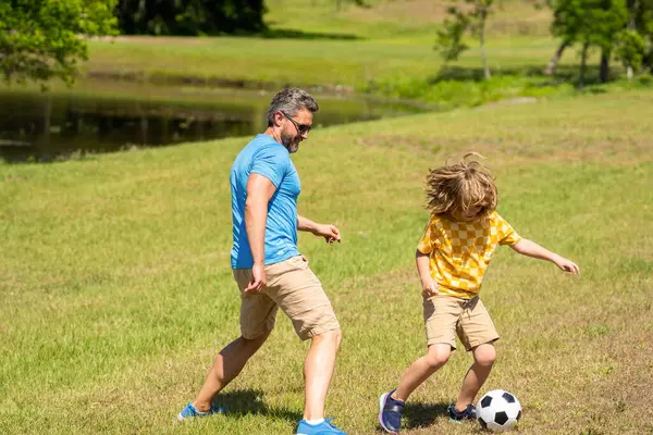 Fatherhood in outdoor of daddy and son kid. daddy with son improve fatherhood. Outdoor adventures of daddy and son fatherhood together. football family team of father and son. soccer ball.