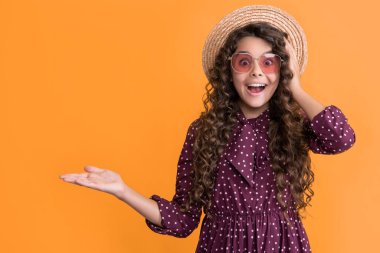 Hasır şapkalı, güneş gözlüklü, uzun esmer kıvırcık saçlı çocuk şaşırdı. Boşluğu kopyala.