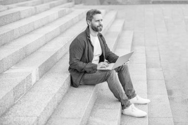 Bilgisayarlı neşeli adamın blog 'u. Blog yazma konsepti. Adam dışarıda dizüstü bilgisayarda blog yazıyor. Bilgisayarlı adam çevrimiçi blog yazıyor.