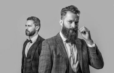 Bıyıklı smokin giyen beyefendi gri arka planda izole edilmiş. Smokinli iki beyefendi. Smokin giyen beyefendilerin stüdyo fotoğrafı. Resmi takım elbiseli zarif beyefendiler..