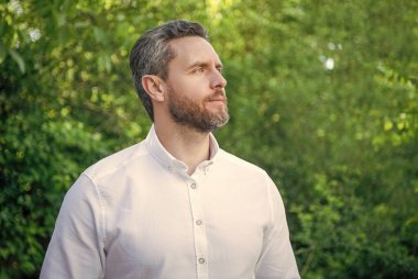 Handsome businessman man looking aside natural background.