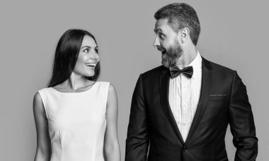 Resmi smokinli sürpriz çift. Resmi smokinli çiftin stüdyo fotoğrafı. Zarif çift resmi smokin giyer. Gri arkaplanda izole edilmiş resmi smokin çifti.