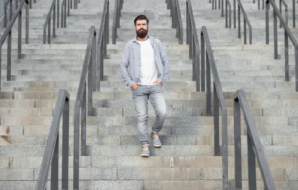 Sakallı adam aşağı iniyor. Sakallı bir adam. Hipster adam merdivenlerden aşağı in..