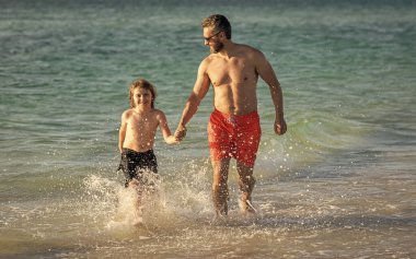 Baba oğul, yaz tatilinin tadını çıkarıyor. Denizdeki baba ve oğul arasında özel anlar. Baba oğul maceraları. Koşulsuz sevgi. Baba, baba, baba, oğul deniz sahilinde koşuyor..