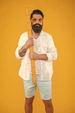 Adam ölçüm cetvelini sarıda izole etti. Adam stüdyoda cetvel ölçer tutuyor. Adam arka planda cetveli tutuyor. Ölçü cetveli tutan adamın fotoğrafı.