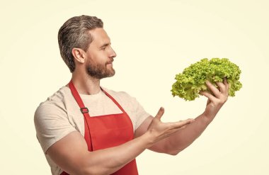 Önlüklü bir adam marul sunuyor..