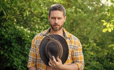 Adam kovboy şapkası tutuyor. Kareli gömlekli seksi kovboy. Kovboy şapkası.