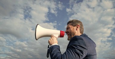 businessman shout in loud hailer on sky background.