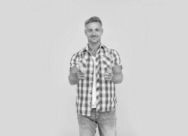 Sarı arka planda kır saçlı mutlu olgun bir adam. işaret parmağı.