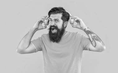 Yüksek sesli müzikle bağıran adamın stüdyo çekimi. Sinirli adamın sarı kulaklıklarda yüksek sesli müziği var. Sinirli adam kulaklıkla yüksek sesle müzik dinler. Yüksek sesli kulaklıklı rahatsız bir adam..