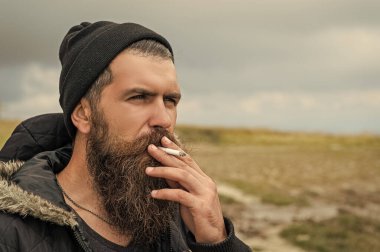 man with beard smoking cigarette, advertisement. bearded man smoking cigarette. photo of man smoking cigarette in the mountain. man smoking cigarette outdoor.