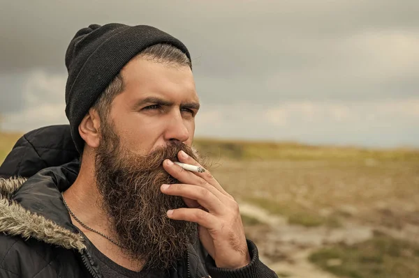 man with beard smoking cigarette, advertisement. bearded man smoking cigarette. photo of man smoking cigarette in the mountain. man smoking cigarette outdoor.