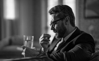 İş adamının ağrı kesici alırken başı ağrıyor. İş adamının baş ağrısı kesicili fotoğrafı. Baş ağrısı olan bir iş adamı ağrı kesici alıyor. Baş ağrısı olan bir iş adamı ağrı kesici alıyor.