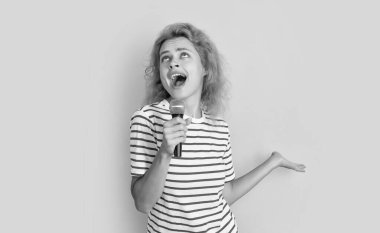 Sarı arka planda izole bir şekilde eğlenen kadın şarkıcı. Genç şarkıcı kadın stüdyoda şarkı söylüyor. Mikrofonlu kadın şarkıcı.