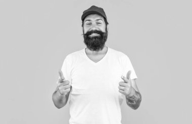 Stüdyodaki sakallı teslimatçı, parmakla işaret ediyor. Arka plandaki sakallı teslimatçı. Sakallı teslimatçının şapkalı fotoğrafı. Sarıda izole edilmiş sakallı teslimatçı..