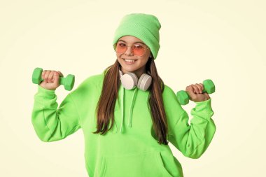 Müzik ve spor merdivenleri olan pozitif bir genç kız. Beyaz arka planda izole edilmiş fitness müziği olan genç kız. Fitness kızı stüdyoda müziği sever. Genç bir kızın fotoğrafı fitness müziğini sever..