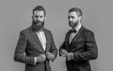 Smokinli karizmatik adamlar stüdyoda. Smokinli adamlar arka planda. Smokinli adamların fotoğrafı var. Smokinli adamlar griden izole edilmiş..