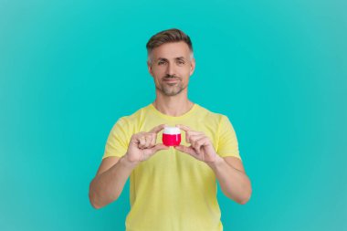 Günlük alışkanlık ve kişisel bakım. Cilt güzelliği. Erkek güzellik kozmetiği. Erkek kozmetik ürünü sunan adam. İzole edilmiş yüz kremi gösteren adam. Olgun adam cilt kremi kullanır. Cilt bakımını takip et.